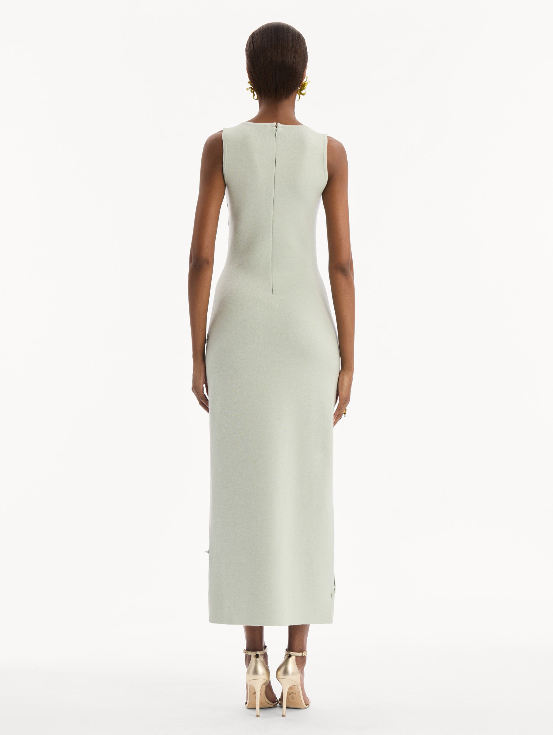 The model is wearing the Hibiscus Embroidered Knit Pencil Dress in Saltwater Blue. Featuring a structural hibiscus embroidery, a scoop neckline, and midi length. Back View.