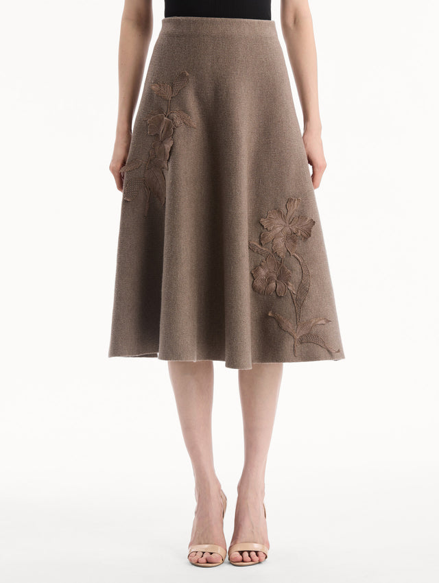 The model is wearing the Hibiscus Embroidered Knit Skirt. Featuring a softly flared silhouette and midi length. Front View.