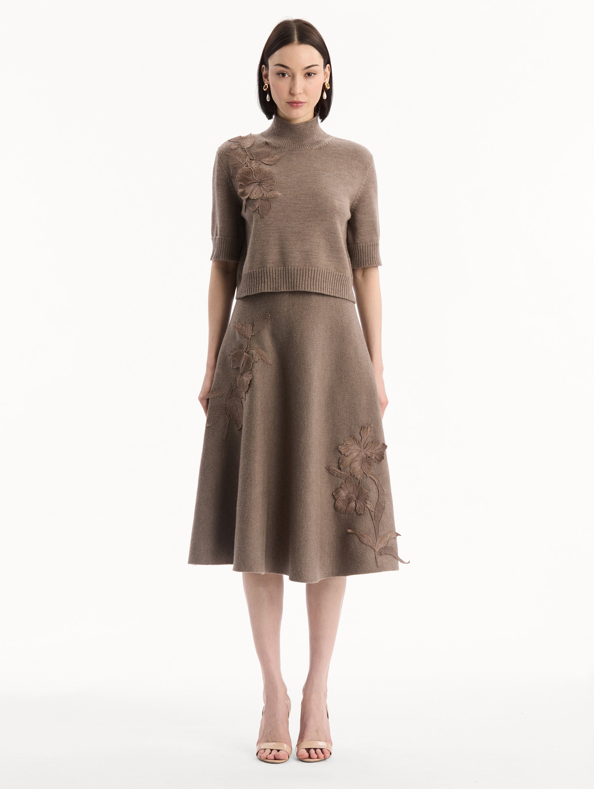 The model is wearing the Hibiscus Embroidered Knit Pullover. Featuring a high neckline and ribbed trim. Front View.