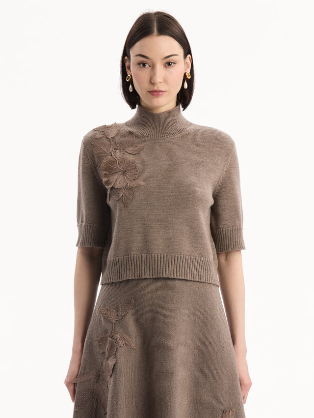 The model is wearing the Hibiscus Embroidered Knit Pullover. Featuring a high neckline and ribbed trim. Front View.