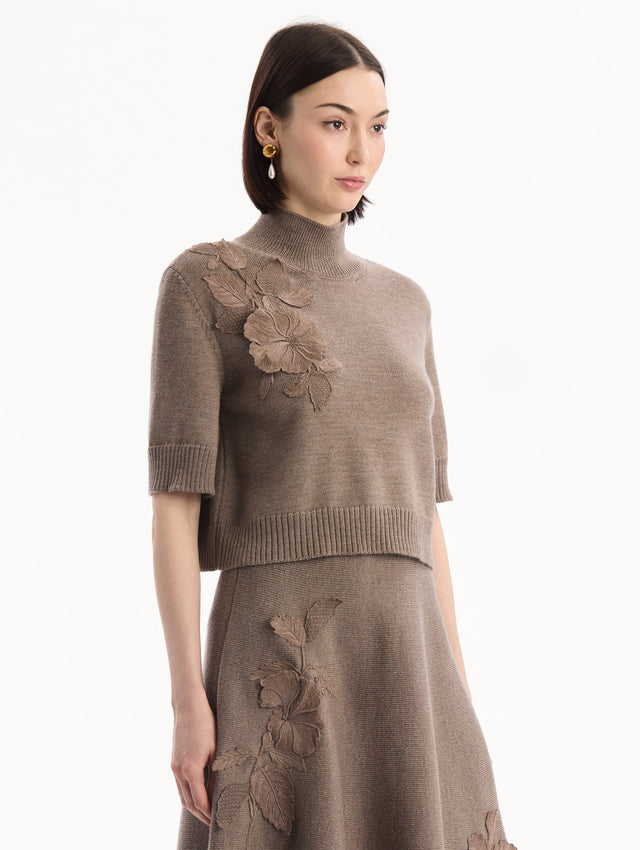 The model is wearing the Hibiscus Embroidered Knit Pullover. Featuring a high neckline and ribbed trim. Side View.