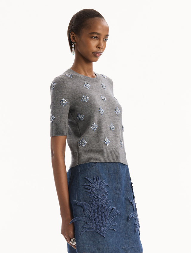 The model is wearing the Crystal Embroidered Pullover in grey with blue crystal embroidered. Featuring a crew neckline and ribbed trims. Side View.