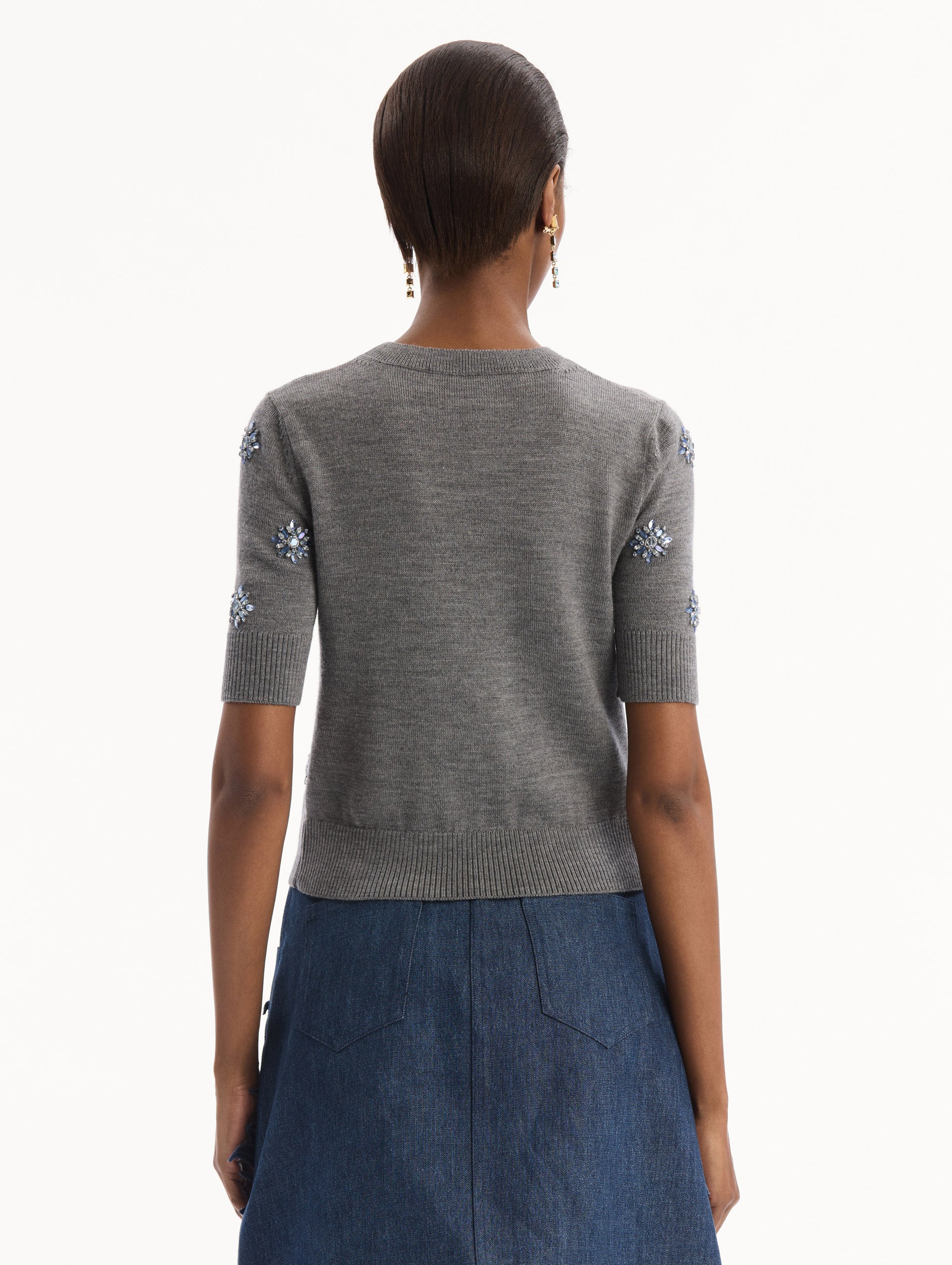 The model is wearing the Crystal Embroidered Pullover in grey with blue crystal embroidered. Featuring a crew neckline and ribbed trims. Back View.