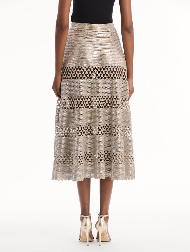 The model is wearing the Silver Foil Midi Skirt. Featuring a tiered silhouette with striped intricate openwork and midi length. Back View.