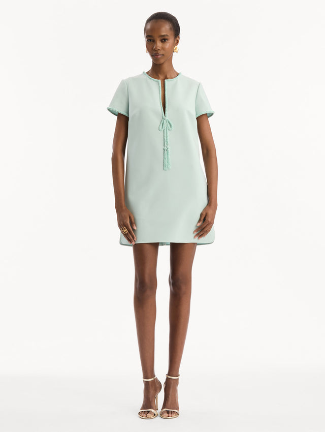 The model is wearing the Beaded Bow-Detail Shift Dress in Saltwater Blue. Featuring a beaded bow detail at the neckline with tassel ties and subtle trim along the edges. Front View.