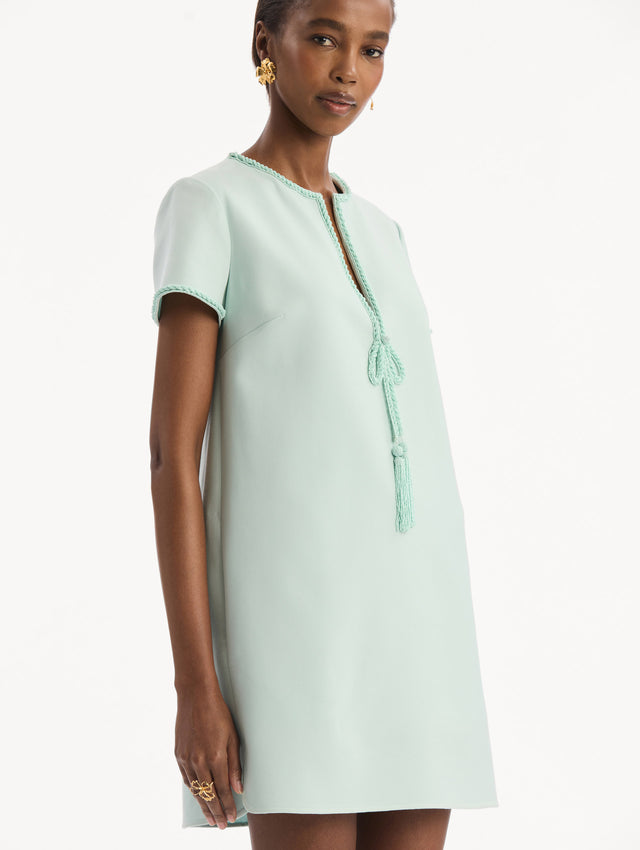 The model is wearing the Beaded Bow-Detail Shift Dress in Saltwater Blue. Featuring a beaded bow detail at the neckline with tassel ties and subtle trim along the edges. Detail View.