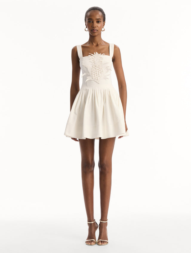The model is wearing the pineapple appliqué denim dress with a structured bodice in the color white. Front view.