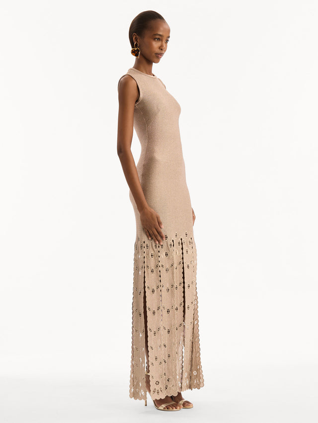 The model is wearing the Pineapple Fringe Metallic Jersey Dress. Featuring shimmering metallic jersey fabrication, a body-skimming silhouette, and pineapple-inspired fringe along the hem. Side View. 