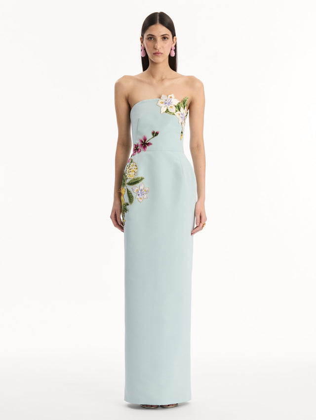 The model is wearing the Dominican Mixed-Floral Embroidered Gown in Saltwater Blue. Featuring Dominican floral embroidery, strapless neckline, and long, column silhouette. Front View.