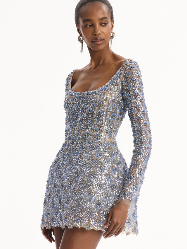 The model is wearing the Crystal & Glass Embroidered Cocktail Dress. Featuring a scoop neckline, long sleeves, and mini length. Detail View.