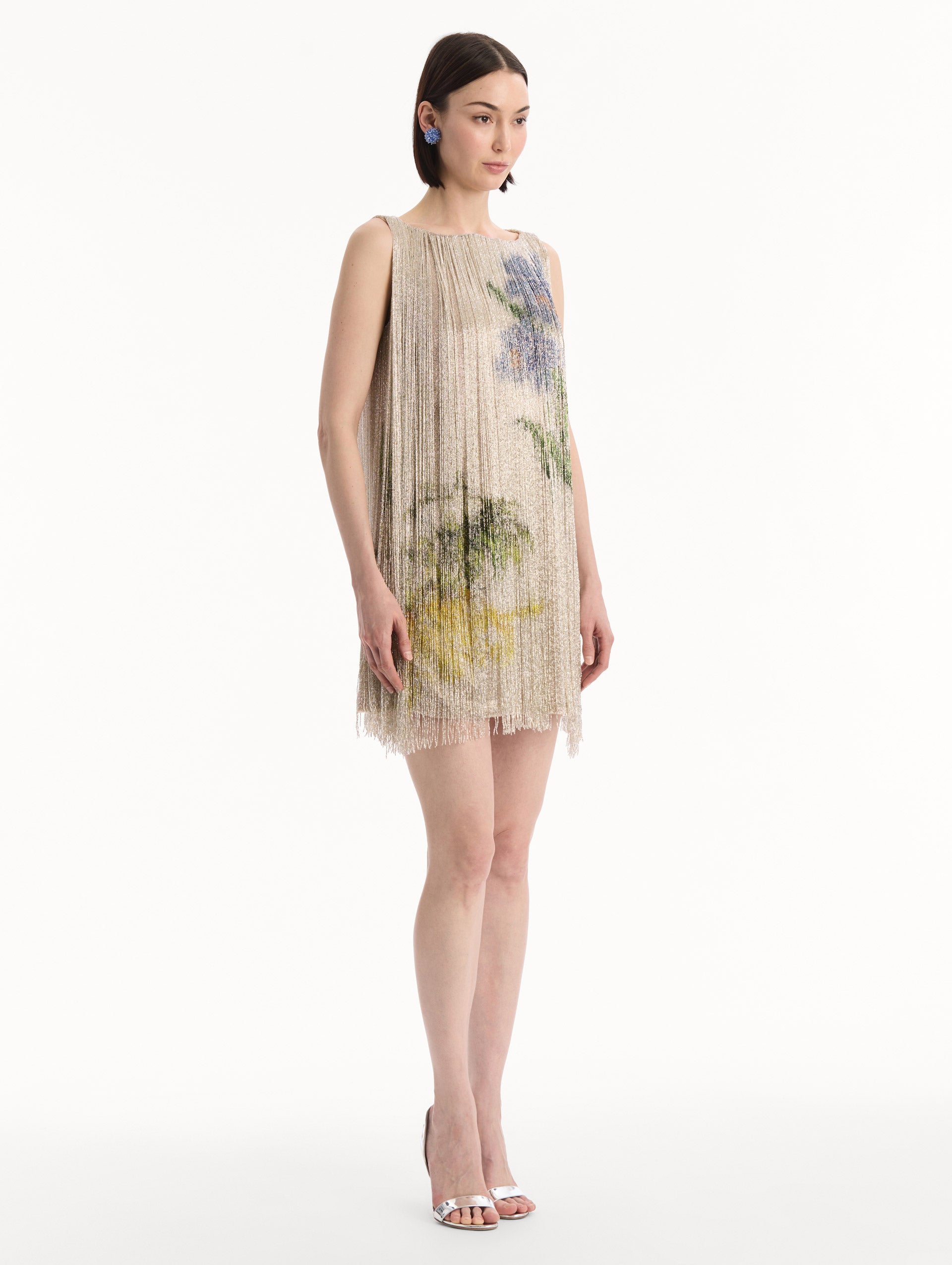 The model is wearing the Chiné Hibiscus Beaded Fringe Shift Dress. Featuring layers of beaded fringe and mini length. Side View.