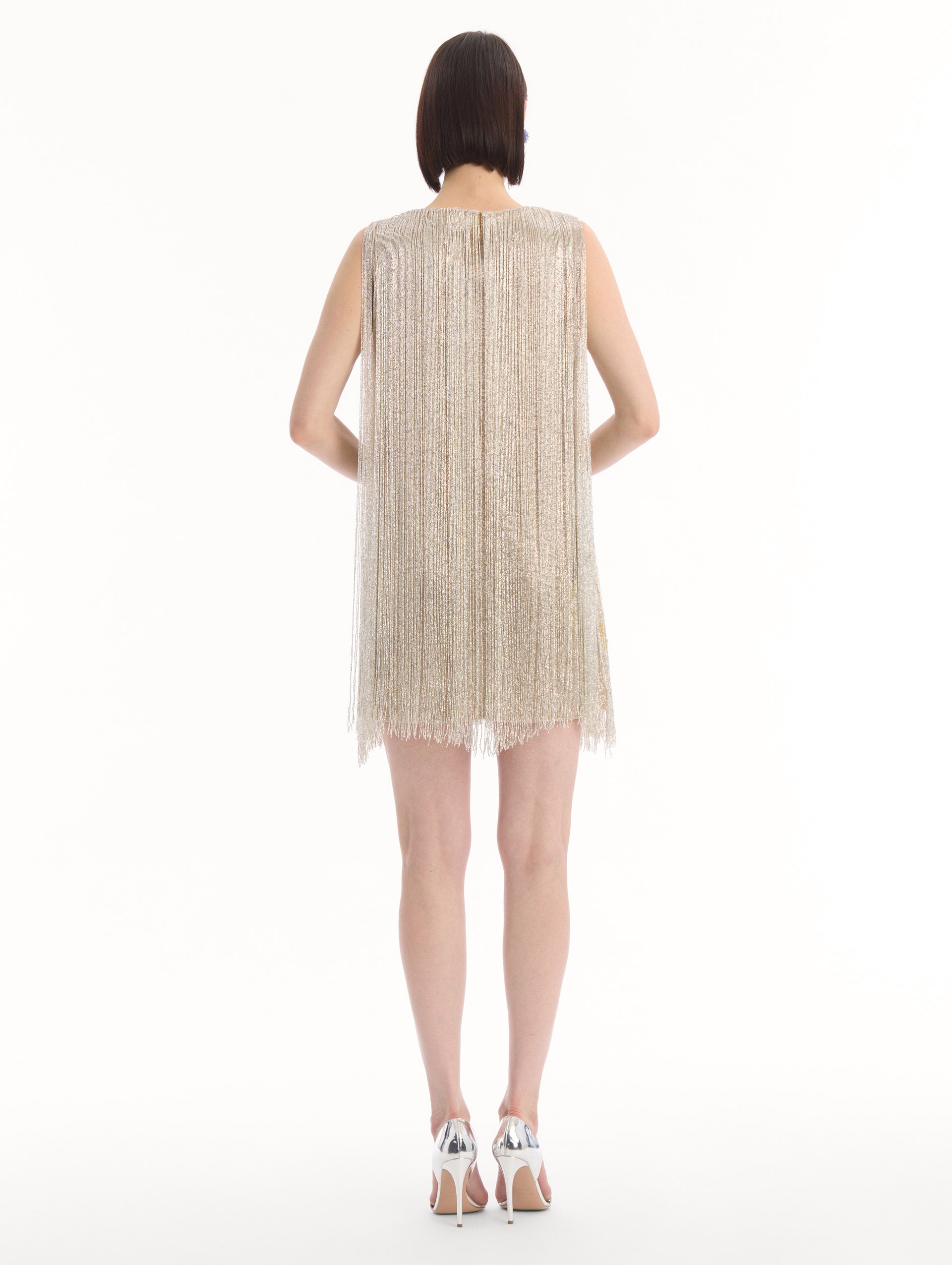 The model is wearing the Chiné Hibiscus Beaded Fringe Shift Dress. Featuring layers of beaded fringe and mini length. Back View.