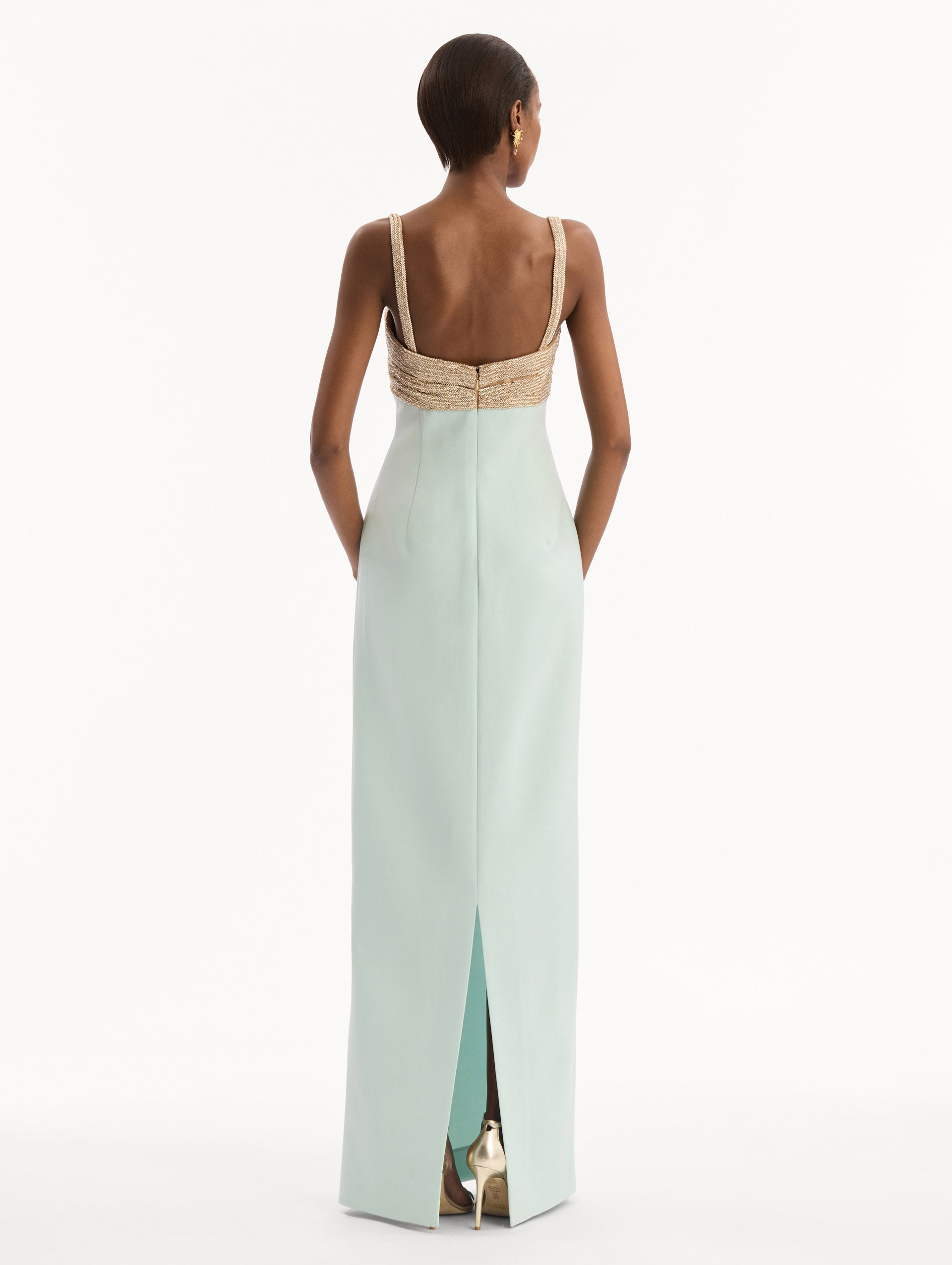 The model is wearing the Twist-Detail Metallic Column Gown in Saltwater Blue. Featuring a metallic twist-detail bodice and long, column silhouette. Back View.