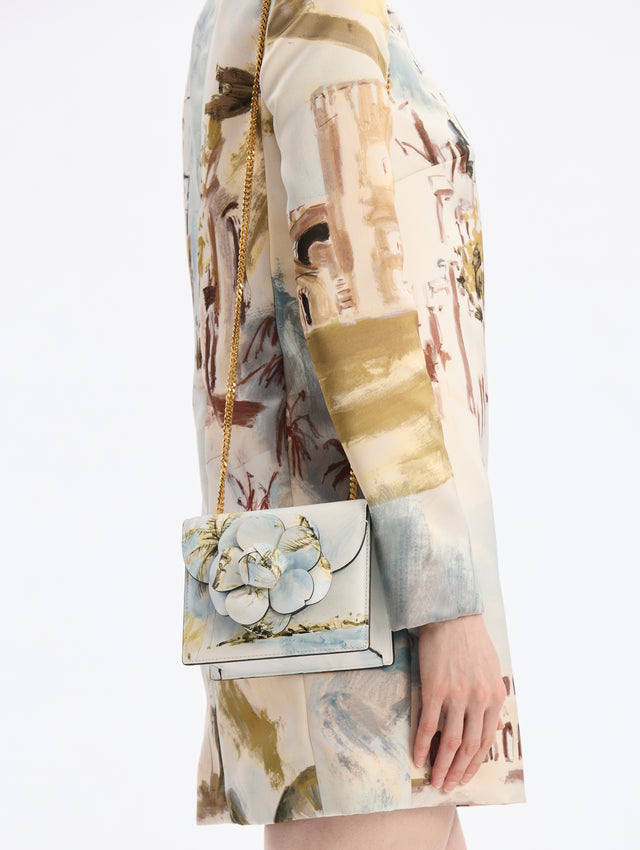 Mini Leather shoulder bag with Dominican Landscape Print. Rectangular with flower closure. Gold Chain strap. Front View.