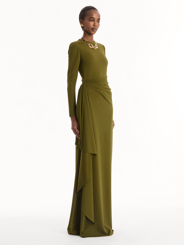 The model is wearing the Drape-Detail Jersey Gown in olive green. Featuring long sleeves, a body-skimming silhouette, gathered detail at waist, and long skirt. Side View.