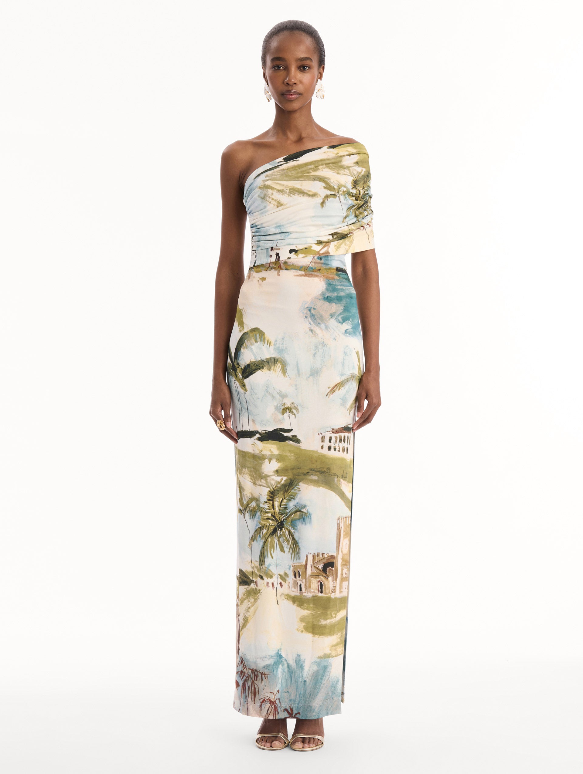 The model is wearing the Dominican Landscape Jersey Gown. Featuring a one-shoulder neckline and long, column silhouette. Front View.