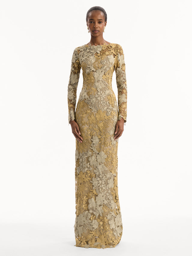 The model is wearing the Hibiscus Metallic Guipure Gown. Featuring metallic guipure lace, long sleeves, a fitted silhouette, and long skirt. Front View.