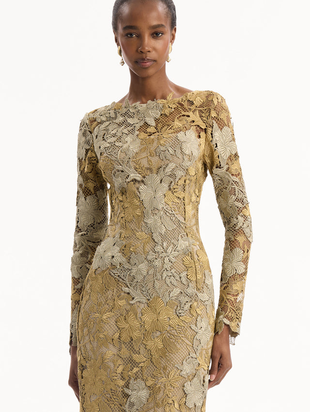The model is wearing the Hibiscus Metallic Guipure Gown. Featuring metallic guipure lace, long sleeves, a fitted silhouette, and long skirt. Detail View.