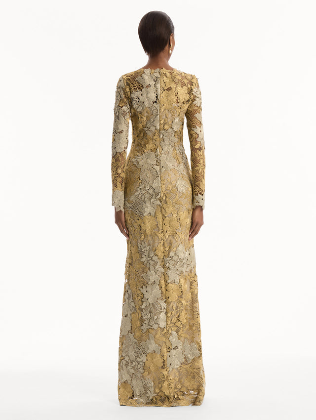 The model is wearing the Hibiscus Metallic Guipure Gown. Featuring metallic guipure lace, long sleeves, a fitted silhouette, and long skirt. Back View.