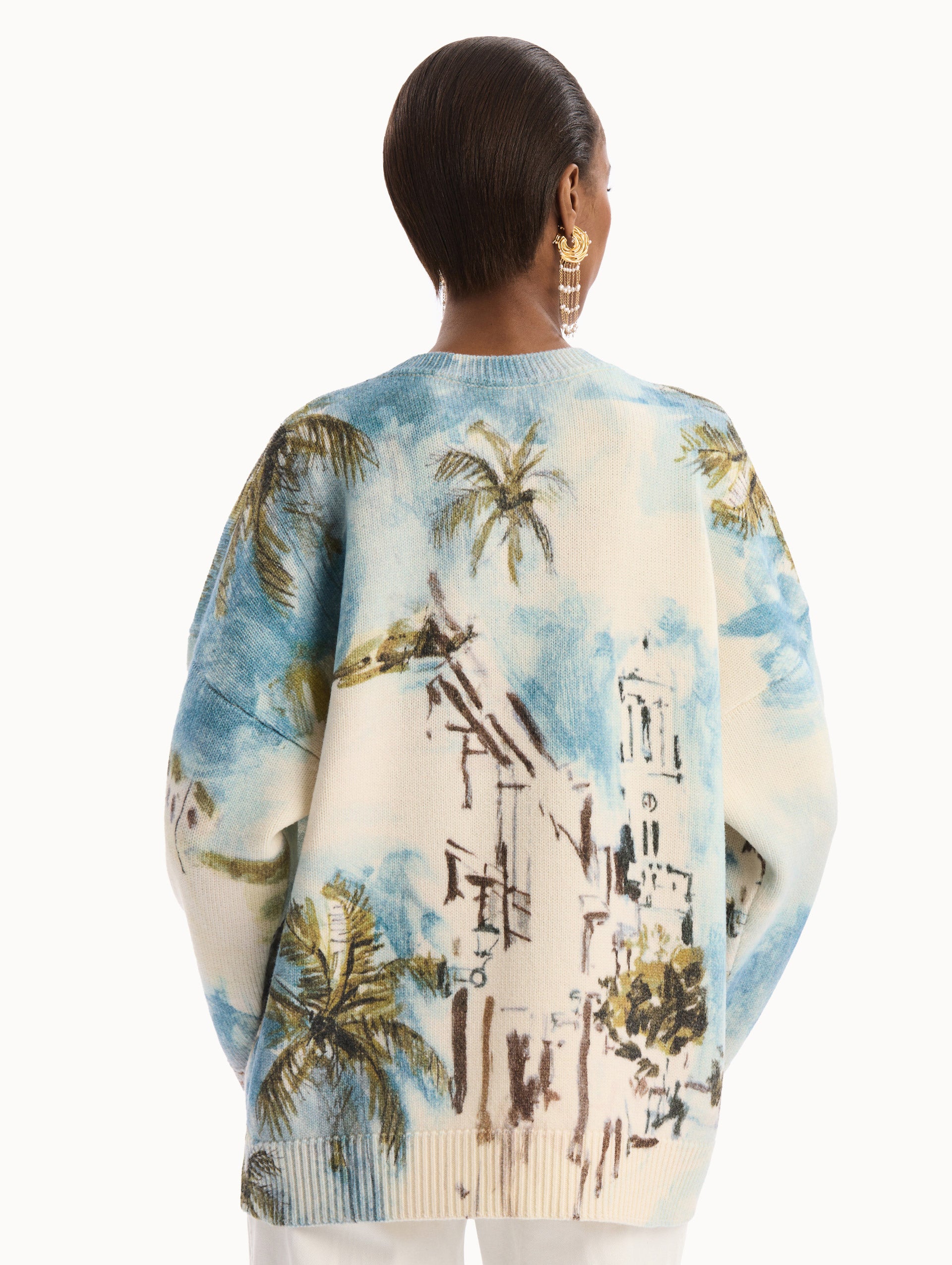 The model is wearing the Dominican Landscape Oversized Pullover. Featuring a crew neckline, long sleeves, ribbed trim, and an oversized fit. Back View.