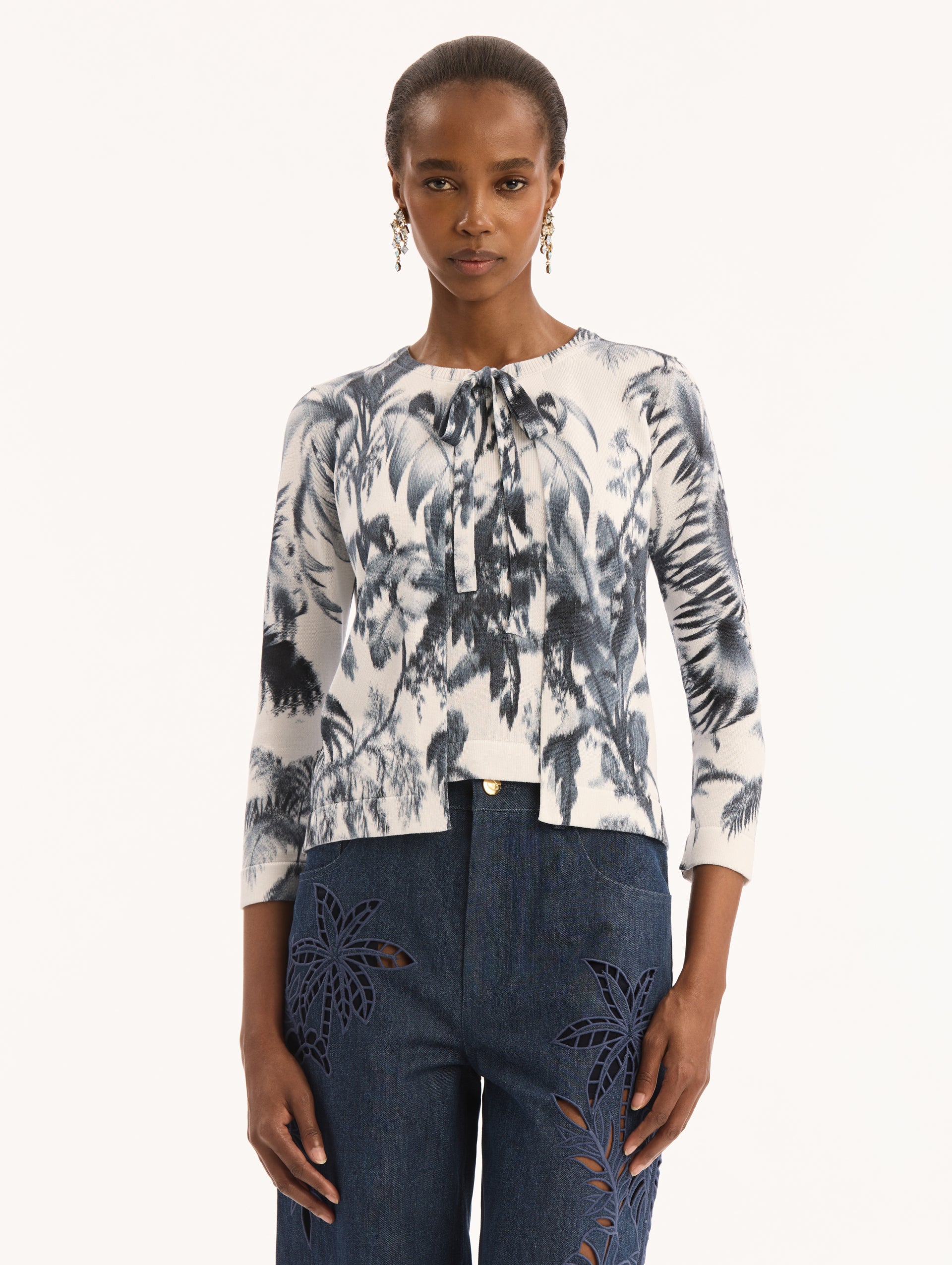 Ivory Three Quarter Length Sleeve Cardigan with Bow Tie Closure at Neck and Navy Chiné Palm Leaves Print. Front View. 