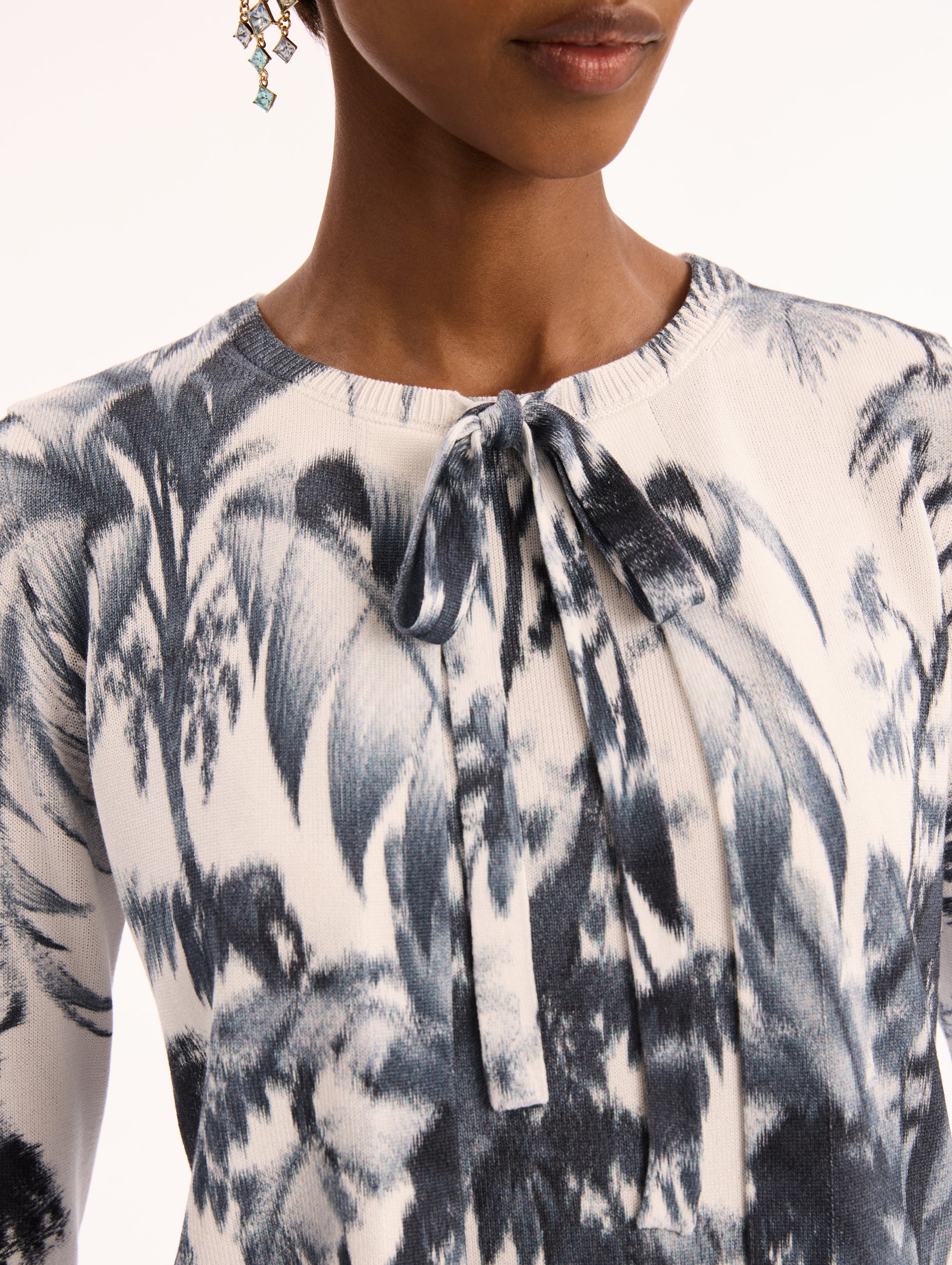 Ivory Three Quarter Length Sleeve Cardigan with Bow Tie Closure at Neck and Navy Chiné Palm Leaves Print. Front View. 