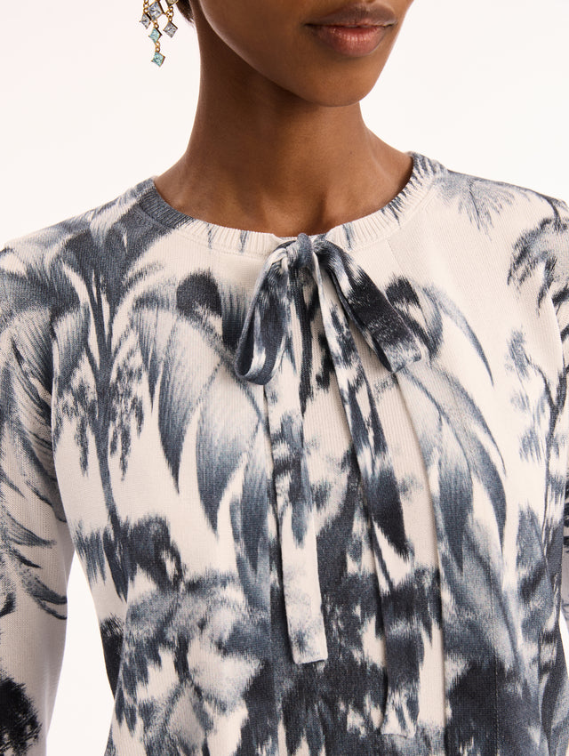 Ivory Three Quarter Length Sleeve Cardigan with Bow Tie Closure at Neck and Navy Chiné Palm Leaves Print. Front View. 