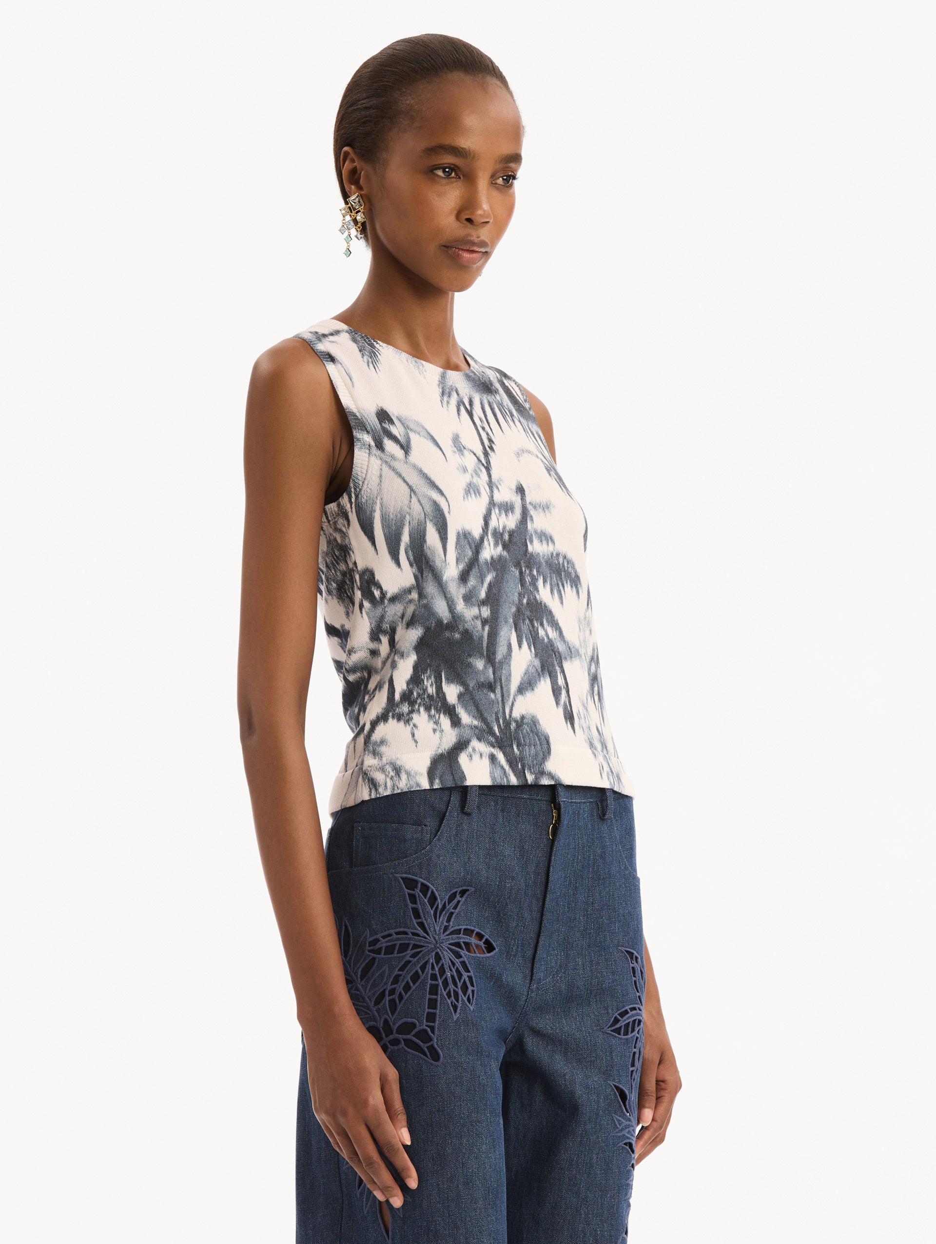 The model is wearing the Chiné Palm Leaves Tank in Navy and White. Featuring a crew neckline and banded trim. Side View.