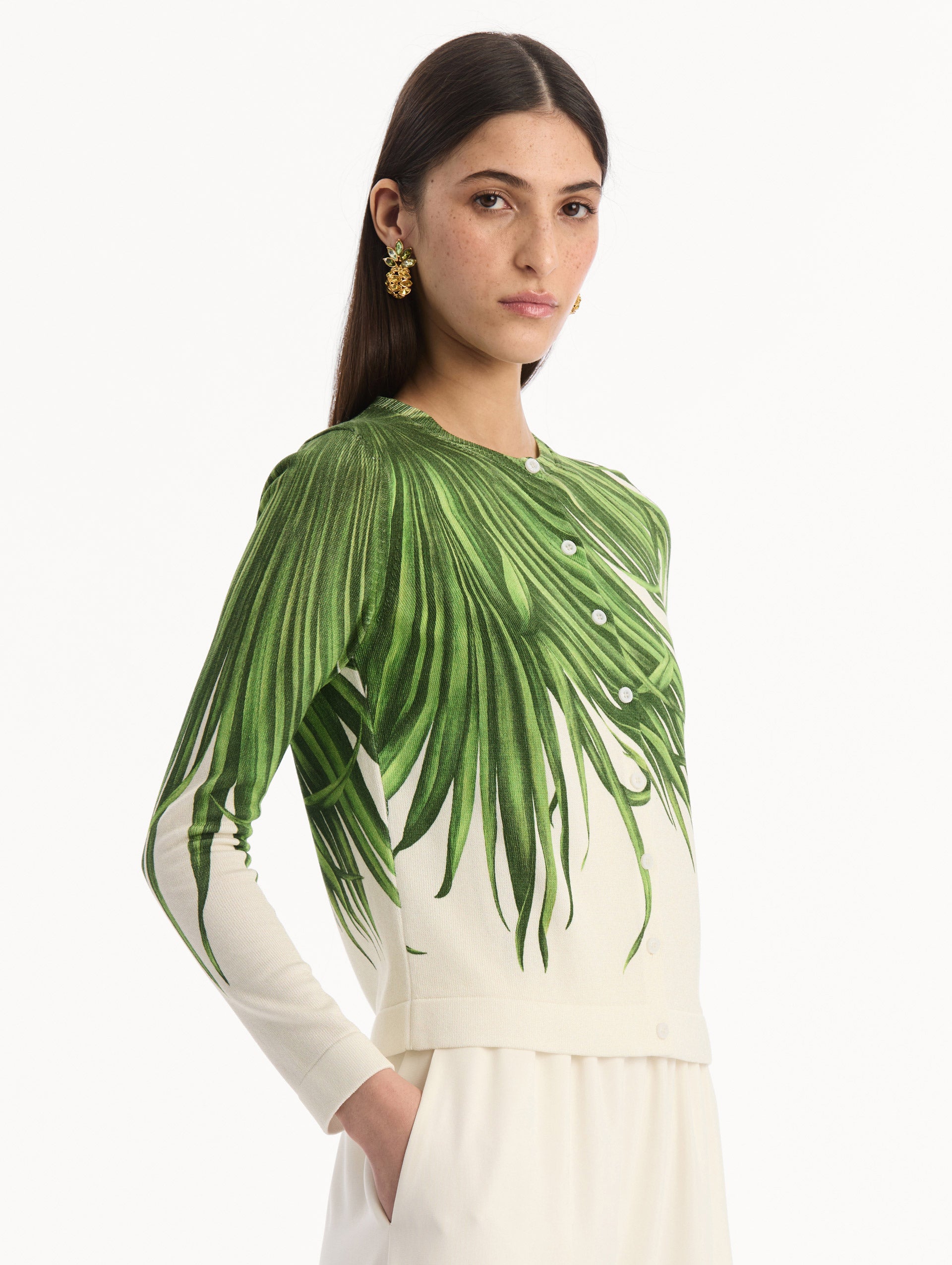 The model is wearing the Palm Leaves Cardigan in Green and Ivory. Featuring front button closures, a crew neckline, long sleeves, and banded trim. Side View.