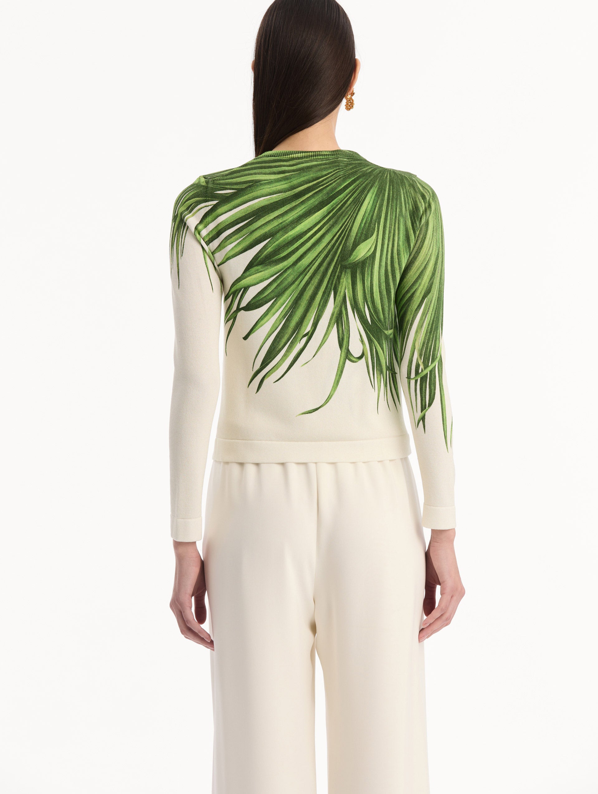 The model is wearing the Palm Leaves Cardigan in Green and Ivory. Featuring front button closures, a crew neckline, long sleeves, and banded trim. Back View.