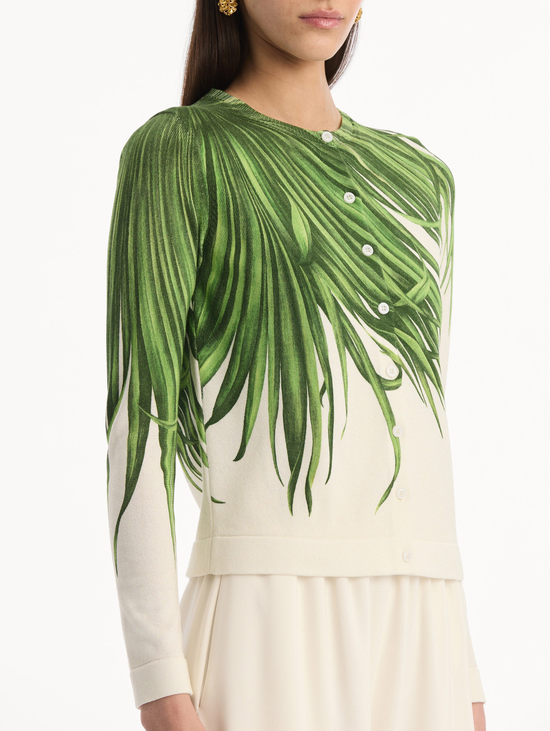 The model is wearing the Palm Leaves Cardigan in Green and Ivory. Featuring front button closures, a crew neckline, long sleeves, and banded trim. Detail View.