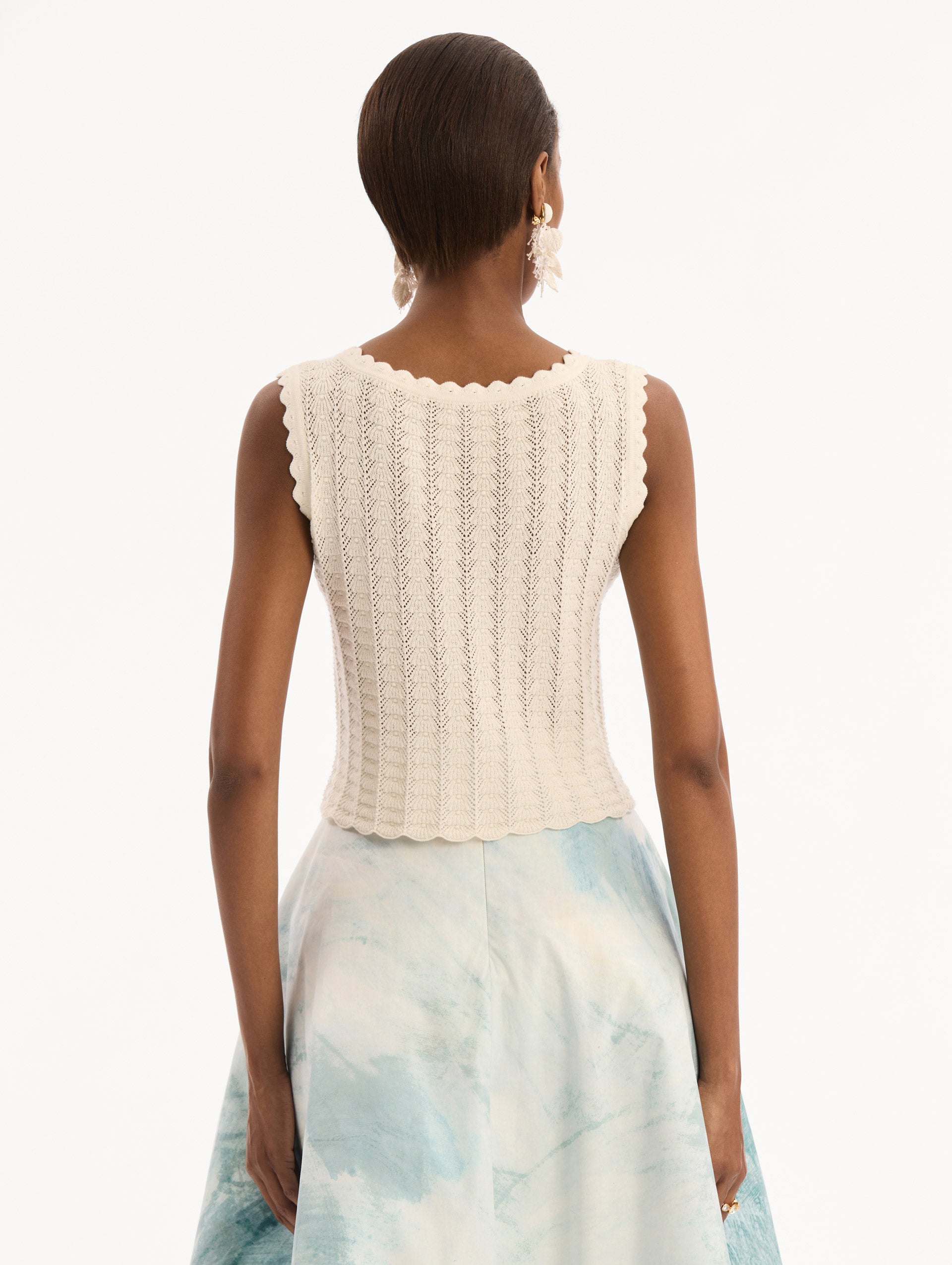 The model is wearing the Pointelle Weave Tank in Ivory. Featuring a scoop neckline, thick tank straps, and scalloped edges. Back View.