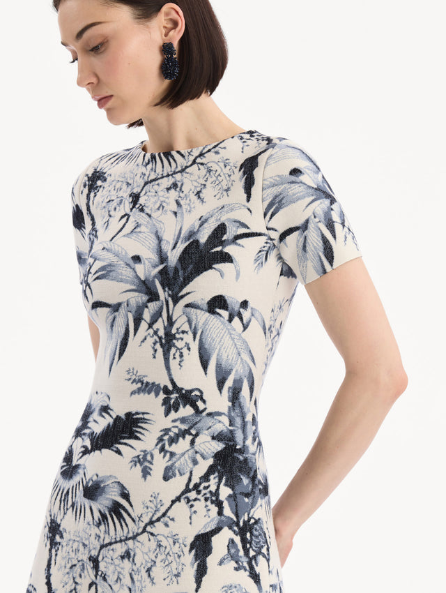 The model is wearing the Chiné Palm Leaves Knit Dress in Navy and Ivory. Featuring a classic silhouette with short sleeves and an A-line midi skirt. Detail View.