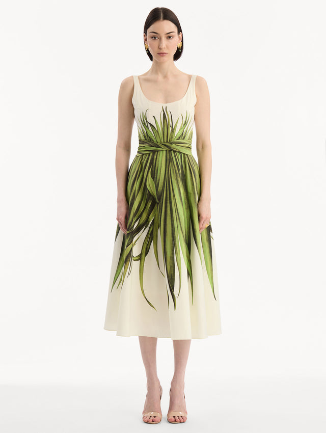 The model is wearing the Palm Leaves Cotton Poplin Dress. Featuring a scoop neckline, tank straps, cinched waist, and midi length. Front View.