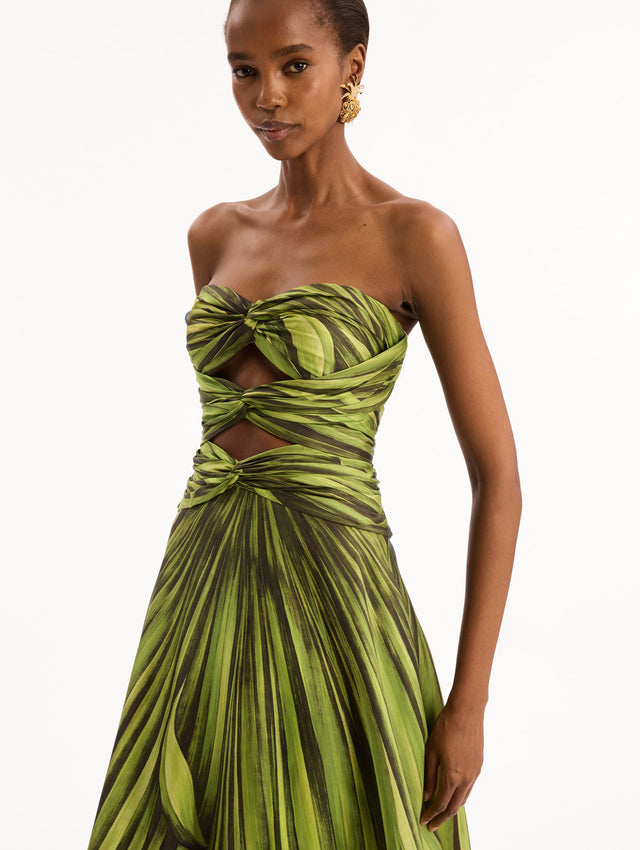 The model is wearing the Palm Leaves Silk Twill Cocktail Dress. Featuring a strapless silhouette, subtle cut-outs at the bodice, and a long skirt. Detail View.