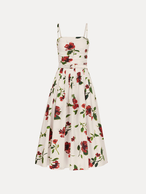 The Hibiscus Cotton Poplin Dress in white with red hibiscus blooms. Featuring a ruched bodice, tank straps, belt at waist, and full, gathered skirt. Front View.