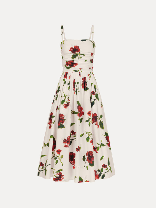 The Hibiscus Cotton Poplin Dress in white with red hibiscus blooms. Featuring a ruched bodice, tank straps, belt at waist, and full, gathered skirt. Front View.