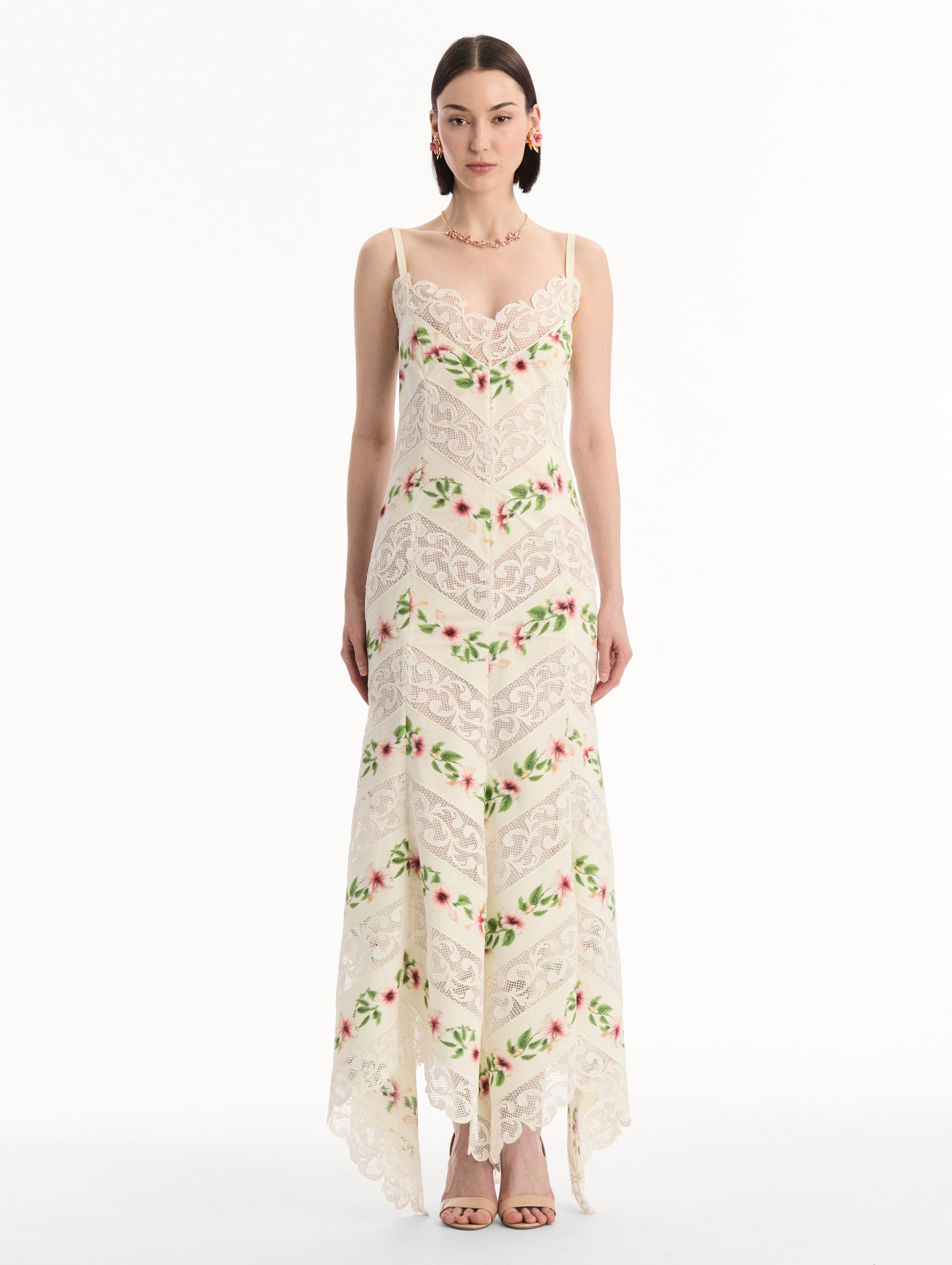 The model is wearing the Chiné Hibiscus Striped Cotton Poplin Dress in Ivory. Featuring a lace neckline, tank straps, and woven hibiscus motifs alternating with panels of faille and guipure lace, creating a striped composition. Front View.