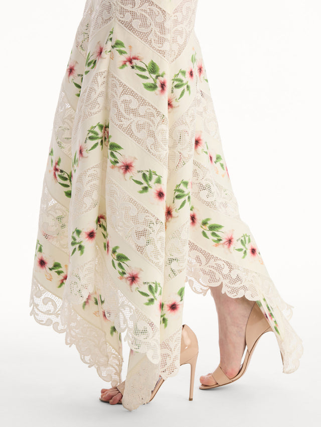 The model is wearing the Chiné Hibiscus Striped Cotton Poplin Dress in Ivory. Featuring a lace neckline, tank straps, and woven hibiscus motifs alternating with panels of faille and guipure lace, creating a striped composition. Detail View.