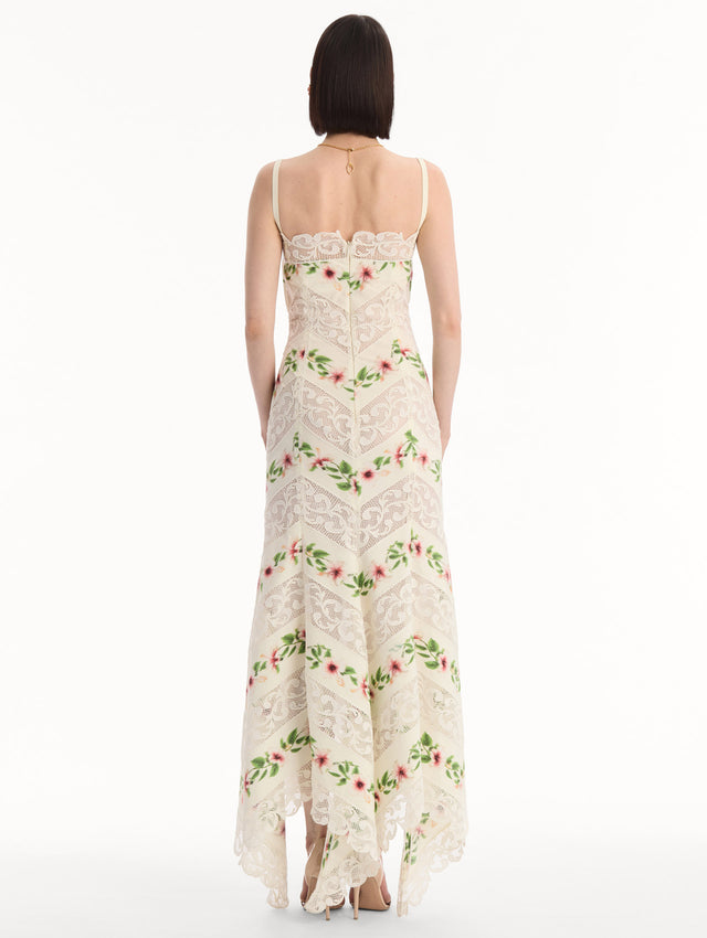 The model is wearing the Chiné Hibiscus Striped Cotton Poplin Dress in Ivory. Featuring a lace neckline, tank straps, and woven hibiscus motifs alternating with panels of faille and guipure lace, creating a striped composition. Back View.