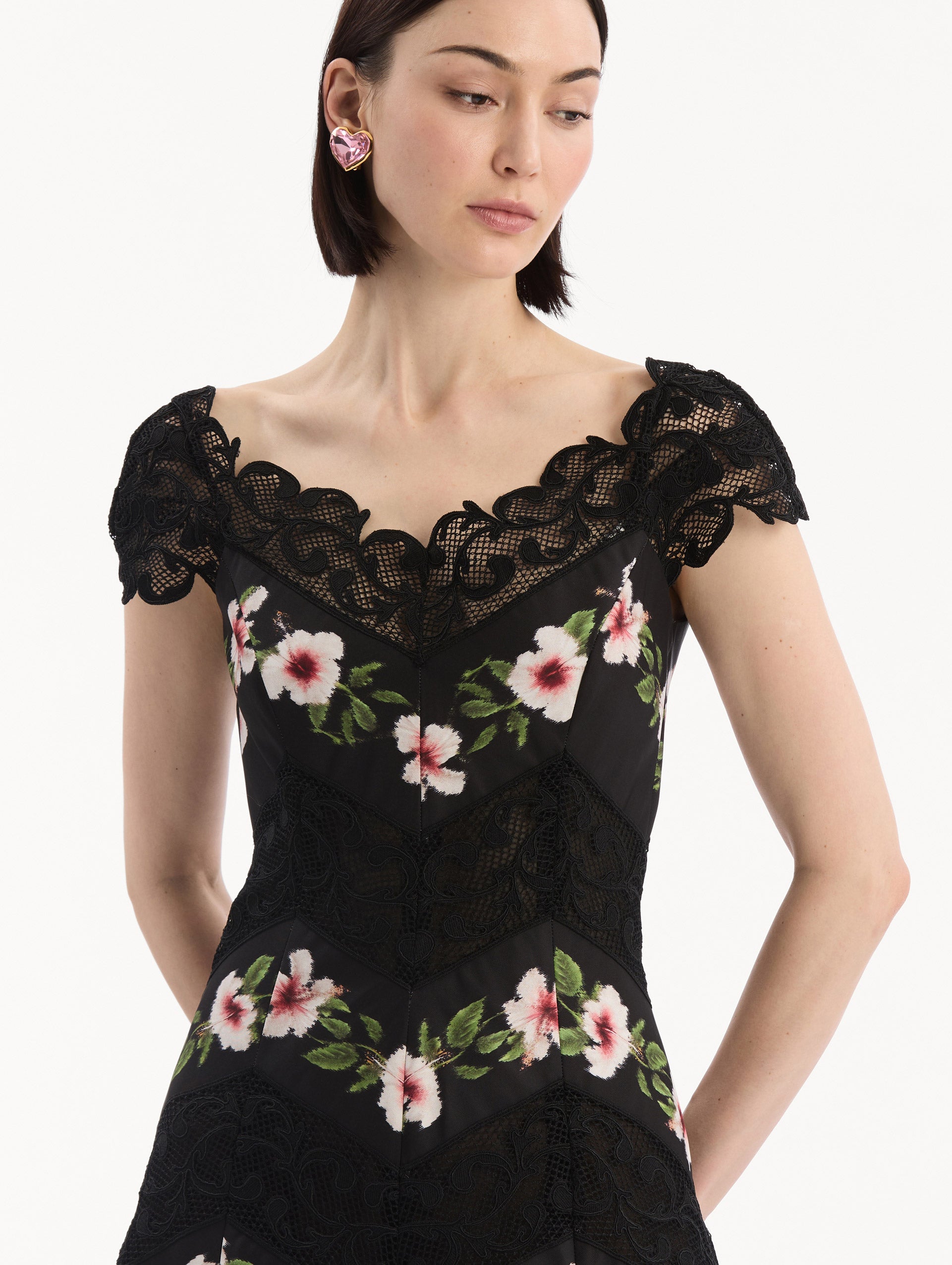 The model is wearing the Chiné Hibiscus Striped Faille Midi Dress in Black. Featuring off-the-shoulder cap sleeves, a midi length, and woven hibiscus motifs alternating with panels of faille and guipure lace, creating a striped composition. Detail View.