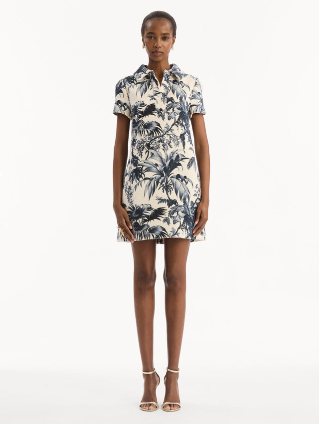 The model is wearing the Chiné Palm Leaves Shift Dress in ivory printed with navy palm leaves. Featuring a classic collar neckline, short sleeves, and mini length. Front View.
