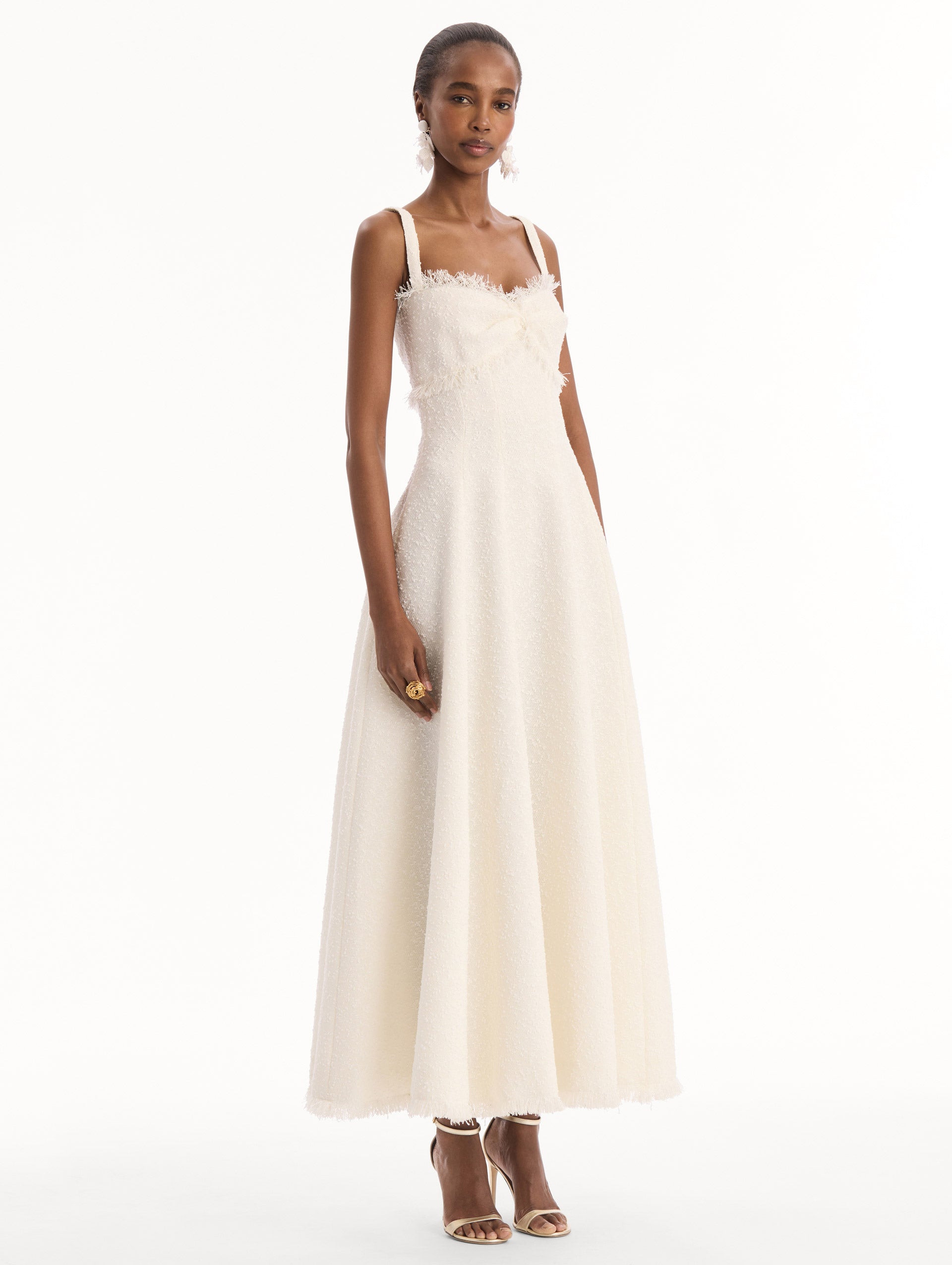 The model is wearing the Slub Wool Tweed Midi Dress in Ivory. Featuring a softly structured silhouette and curved neckline accented with delicate fringe detailing. Side View.