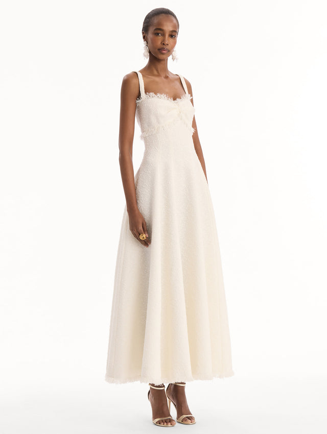 The model is wearing the Slub Wool Tweed Midi Dress in Ivory. Featuring a softly structured silhouette and curved neckline accented with delicate fringe detailing. Side View.