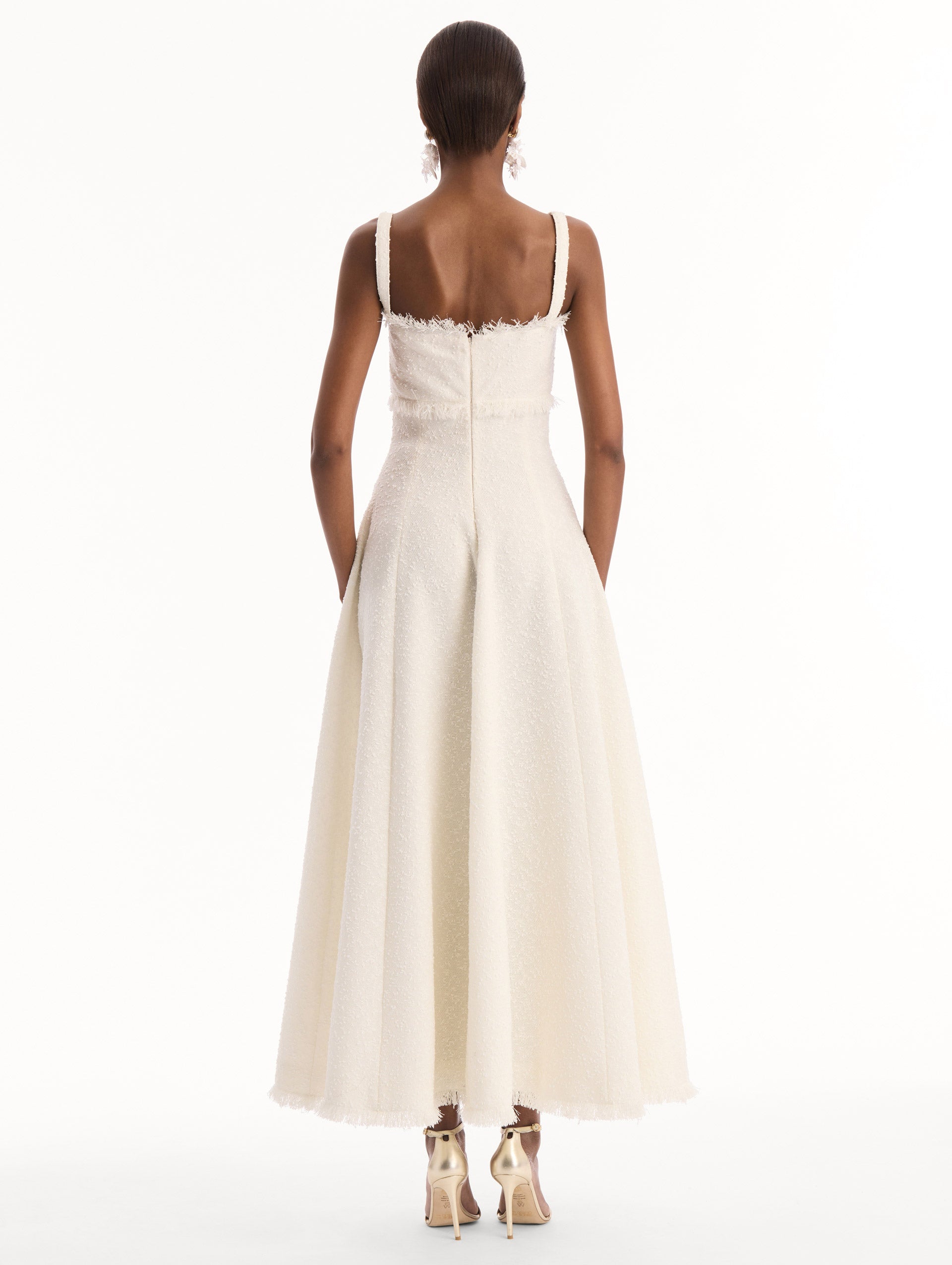 The model is wearing the Slub Wool Tweed Midi Dress in Ivory. Featuring a softly structured silhouette and curved neckline accented with delicate fringe detailing. Back View.