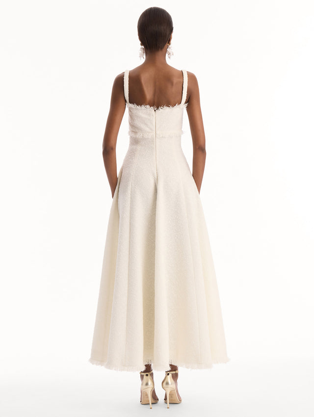 The model is wearing the Slub Wool Tweed Midi Dress in Ivory. Featuring a softly structured silhouette and curved neckline accented with delicate fringe detailing. Back View.