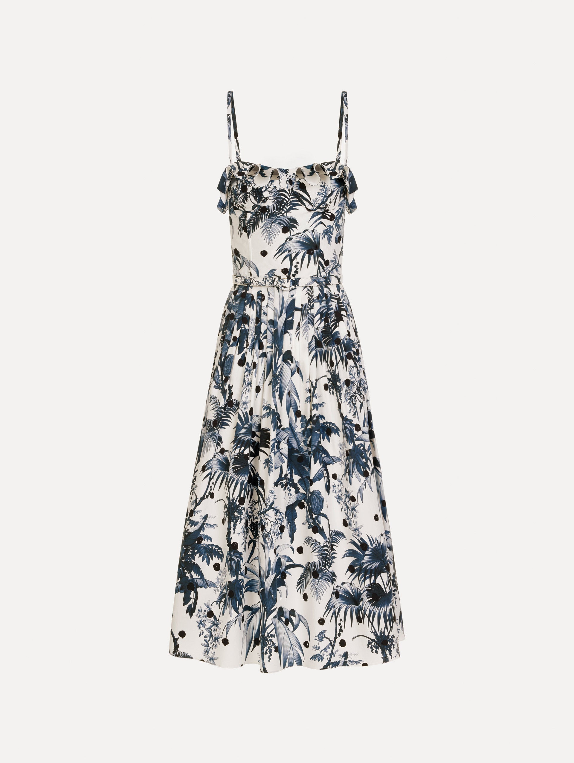 The Dotted Palm Leaves Cotton Poplin Sleeveless Dress in Navy Blue and White. Featuring a palm leaves print, ruffled top, delicate straps, belt at waist, softly structured bodice, and gathered skirt. Front View.