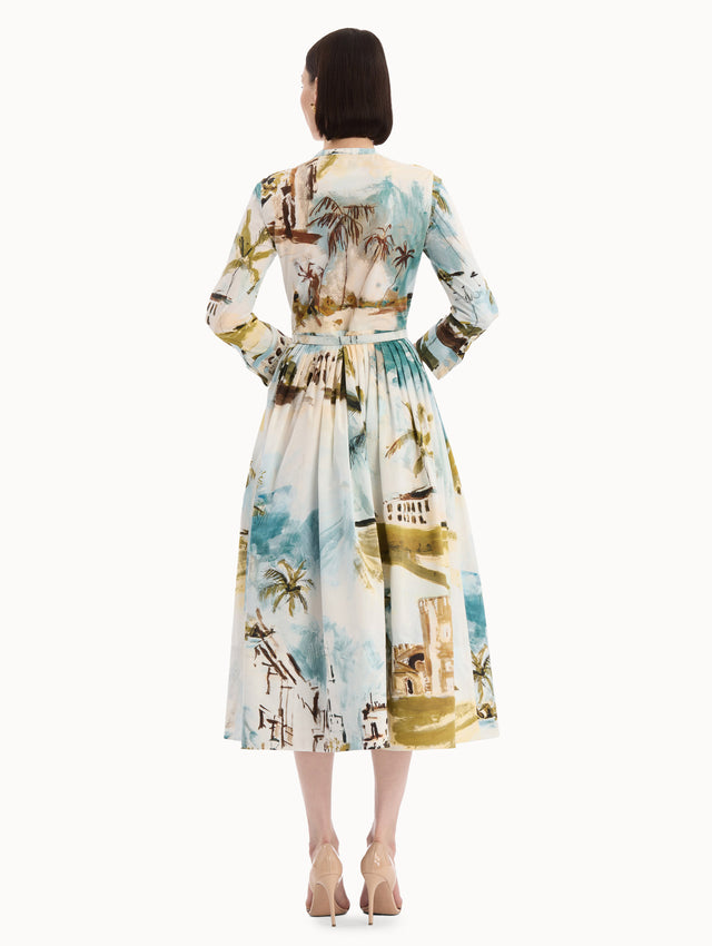 The model is wearing the Dominican Landscape Cotton Poplin Short-Sleeve Dress printed with the Dominican landscape. Featuring long sleeves, front-button closure, belt at waist, and pleated midi skirt. Back view.