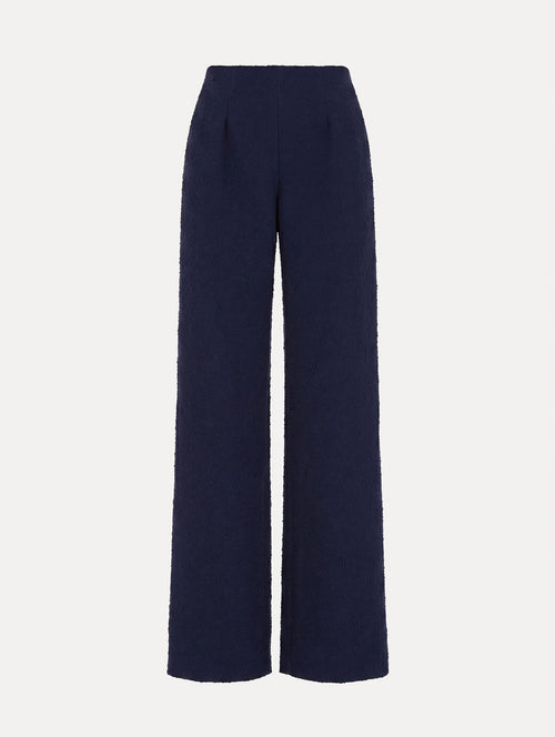 The model is wearing the slub wool tweed wide-leg pant in the color navy with a high-rise waist.