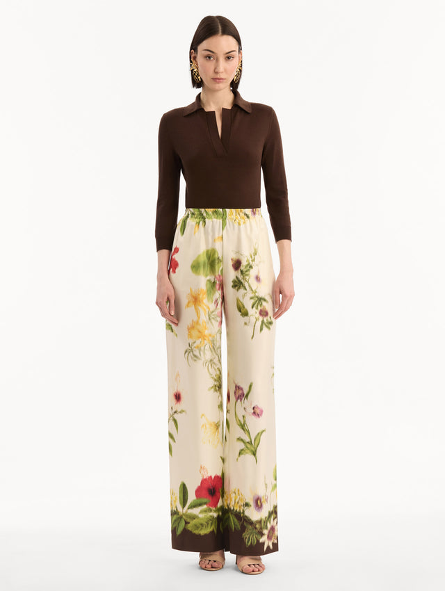 The model is wearing the Dominican Mixed-Floral Wide Leg Pant in ivory printed with an array of Dominican florals. Featuring wide legs and an elastic waistband. Front View.